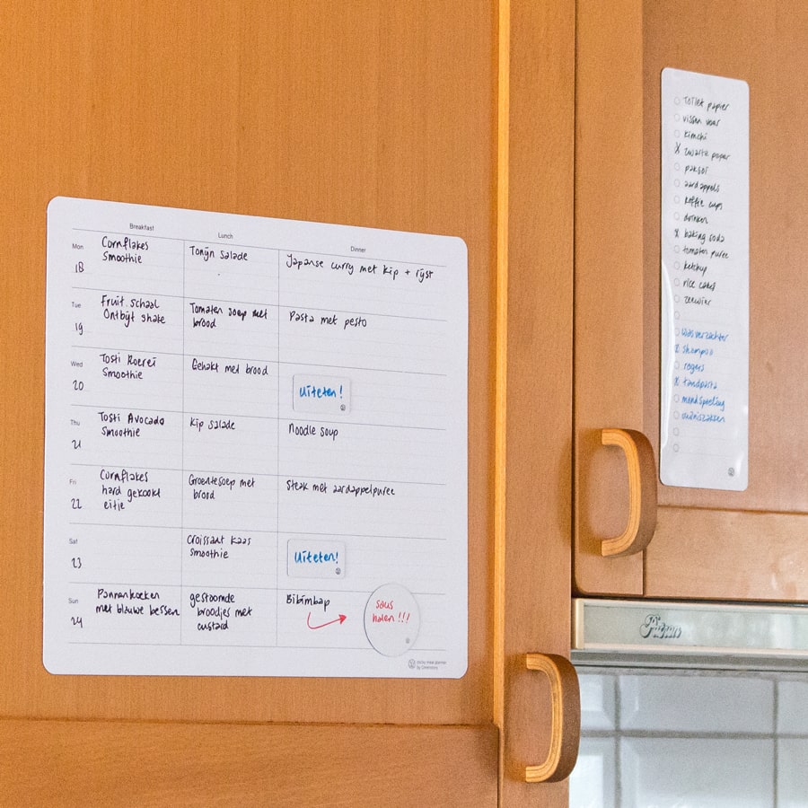Sticky boodschappenplanner en sticky maaltijdplanner op een keukenkast geplakt.