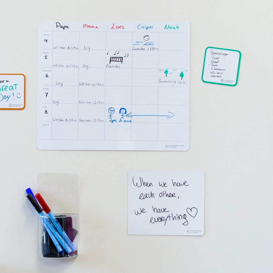Ingevulde familieplanner voor 5 personen geplakt op een kastdeur.