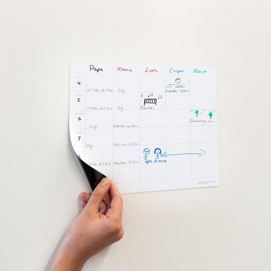 Hand houdt hoekje omhoog van sticky familieplanner voor 5 personen.
